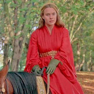 Princess Buttercup The Princess Bride cosplay reference showing the full character look from a side angle, medieval red gown in motion, dark green leather gloves, long blonde hair, and rose gold tiara