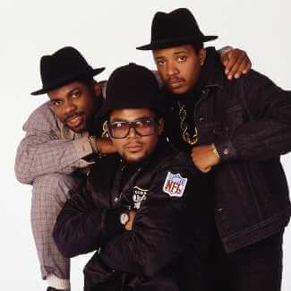 Run-D.M.C. cosplay styling reference showing the full Adidas tracksuit, bucket hat, gold chain and Superstar sneakers