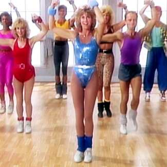 Jane Fonda workout cosplay costume full look with metallic blue leotard, curly brown hair, high-waisted belt, and blue leg warmers