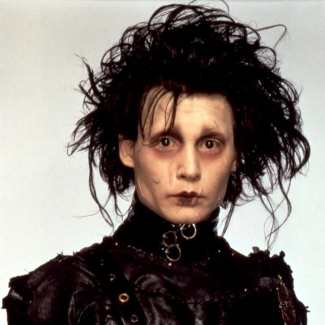 Edward Scissorhands cosplay costume full look — black leather jacket with layered belts and O-rings, wild spiky black wig, pale white face with scar makeup, scissor blade gloves