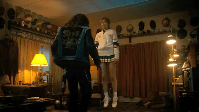 Eddie Munson from Stranger Things Season 4 watching in paralyzed horror as Chrissy begins to levitate, one of the most iconic and dramatic scenes featuring Joseph Quinn's character in his signature Hellfire Club shirt and denim vest costume