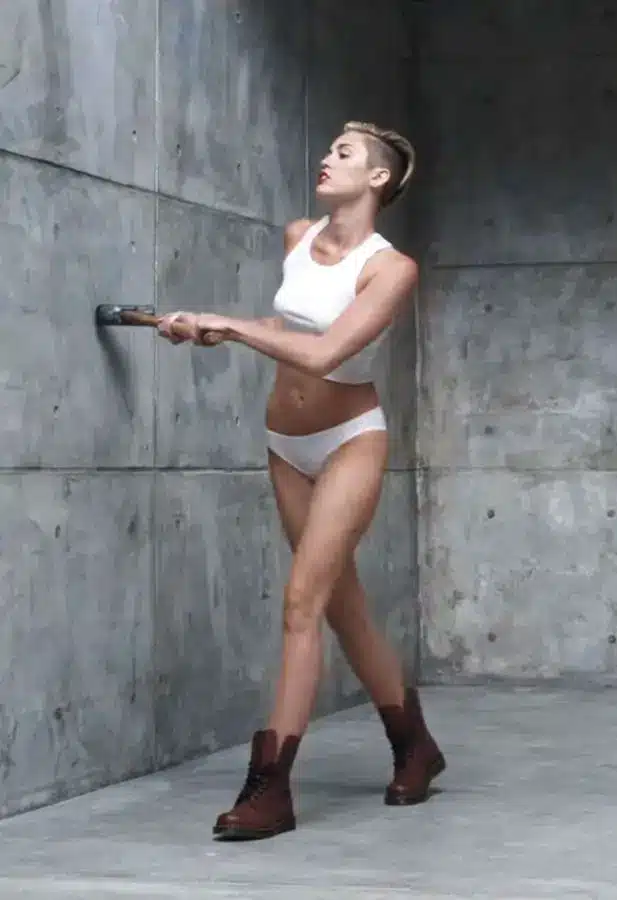 Miley Cyrus in the Wrecking Ball music video holding a sledgehammer in her white outfit, showing the exact look recreated by the Halloween costume
