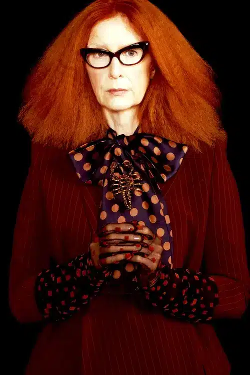 Myrtle Snow in her red dress and black and red scarf, showcasing the AHS Coven character's signature theatrical fashion style