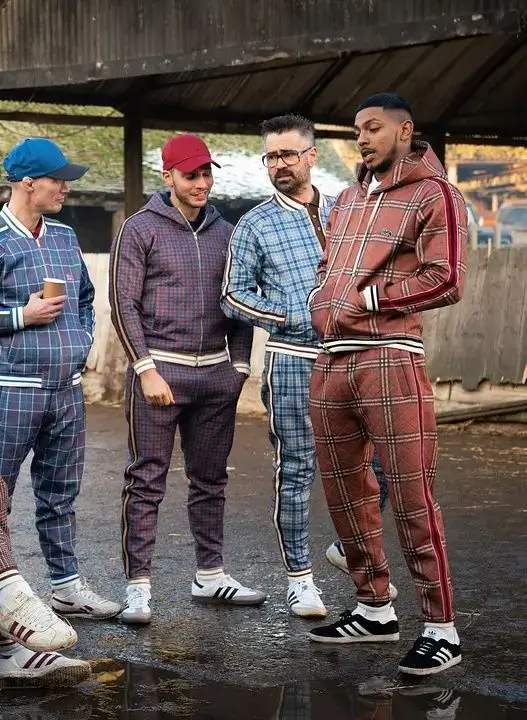 Coach from The Gentlemen with the teenagers from the film, showing the character in his signature patterned tracksuit, hat, and leopard glasses
