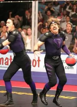 Ben Stiller as White Goodman and Missi Pyle as Fran Stalinovskovichdavidovitchsky mid-game in full Purple Cobras purple and black padding, holding dodgeballs with aggressive expressions