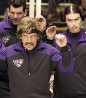 Ben Stiller as White Goodman in a purple and black Purple Cobras track jacket and black headband, staring ahead with an intense expression alongside two teammates making synchronized hand gestures