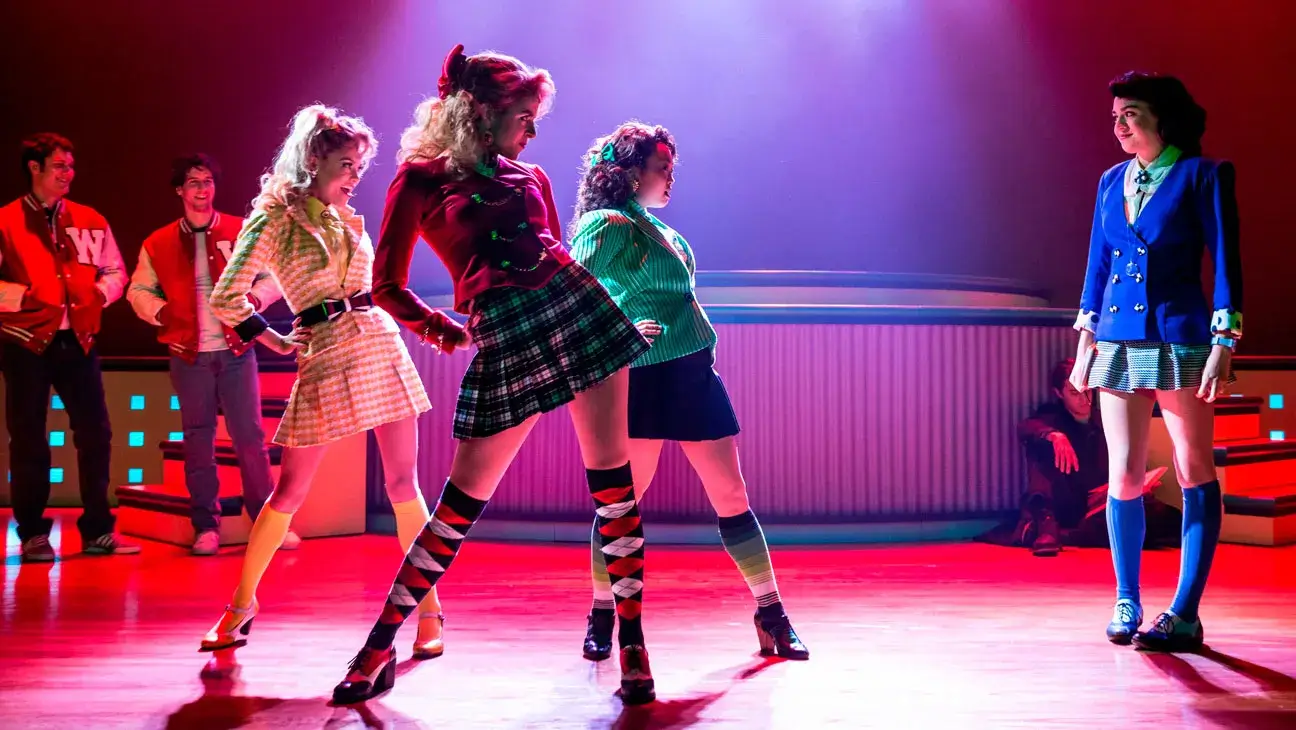 All four Heathers the Musical characters together: Heather McNamara in yellow, Heather Chandler in red, Veronica Sawyer in blue, and Heather Duke in green