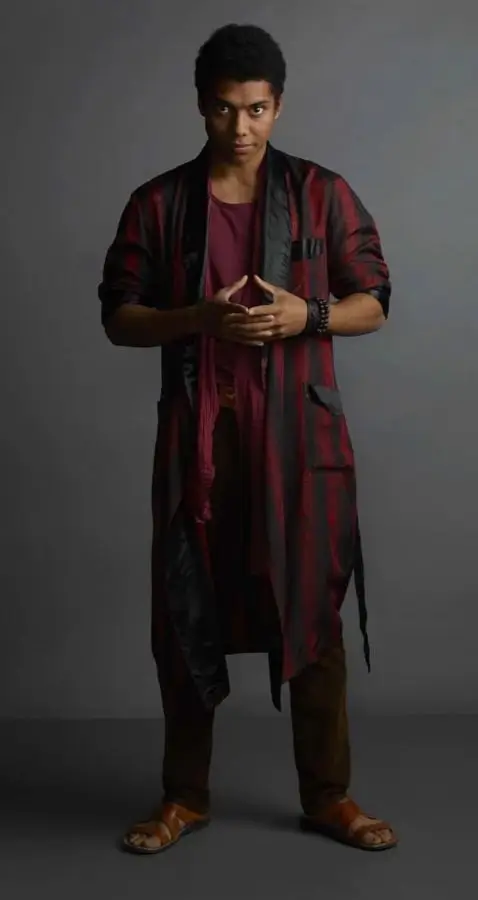 Chance Perdomo as Ambrose Spellman in Chilling Adventures of Sabrina, showing the layered floral shirt under leather jacket, wine red scarf, stacked wrist bracelets, and dark jeans
