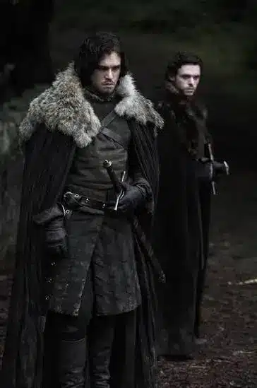 Jon Snow and Robb Stark side by side in Game of Thrones, showing the visual contrast between Night's Watch black and King in the North armor