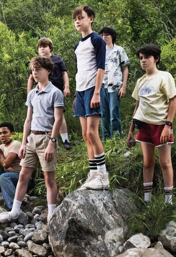 The Losers' Club from IT (2017) standing together, including Eddie Kaspbrak in his pink polo and cargo shorts