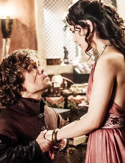 Shae and Tyrion Lannister together in a scene from Game of Thrones, showing the visual contrast between her handmaiden look and his court costume