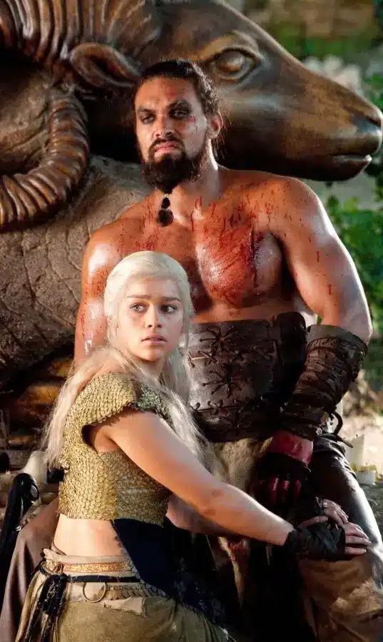 Jason Momoa as Khal Drogo and Emilia Clarke as Daenerys Targaryen in Game of Thrones Season 1, showing the visual contrast between Drogo's Dothraki warrior look and Daenerys's Targaryen costume for a couples Halloween pairing