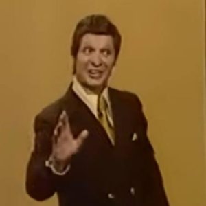 Eduard Khil performing the Trololo vocalise on Soviet television in a dark double-breasted suit and gold tie