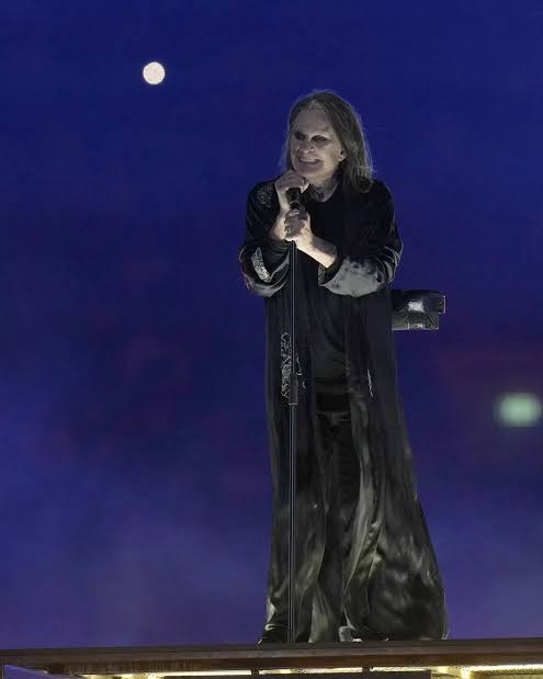 Ozzy Osbourne stage performance costume reference showing black suit and long dark hair