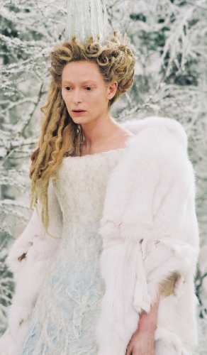 Jadis the White Witch standing in a snowy forest wearing a white fur trimmed cape and ice crystal crown in The Chronicles of Narnia