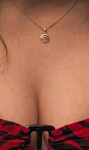 Close-up of the gold spiral swirl pendant necklace worn by Nikki Freeman, detail reference for the costume's jewelry