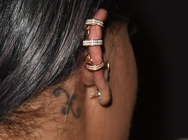 Small Pisces zodiac symbol tattoo behind Rihanna's right ear