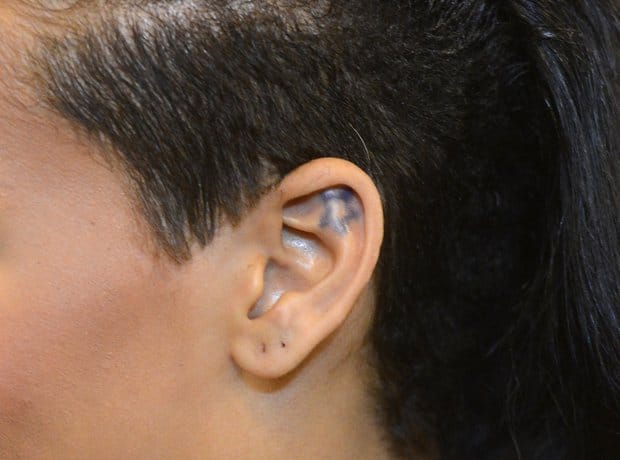 Tiny star outline tattoo inside the curve of Rihanna's left ear