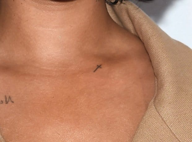 Close-up of the tiny minimalist cross tattoo on Rihanna's left collarbone