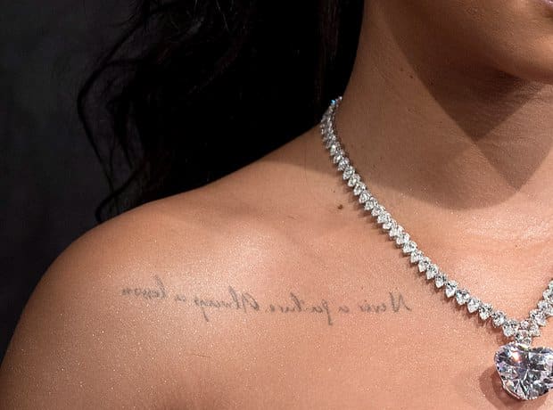 Close-up of Rihanna's backwards script tattoo reading Never a failure, always a lesson under her right collarbone