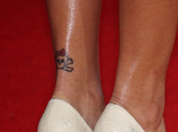 Small skull and crossbones tattoo with a pink bow on the back of Rihanna's ankle