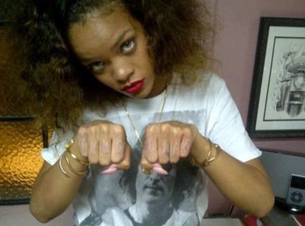 Faint white ink Thug Life lettering across Rihanna's knuckles